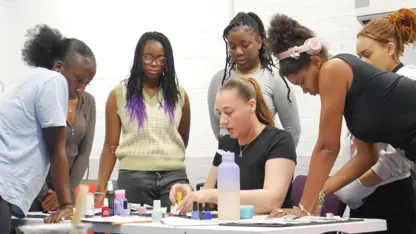 Girs lean over desk watching nail art